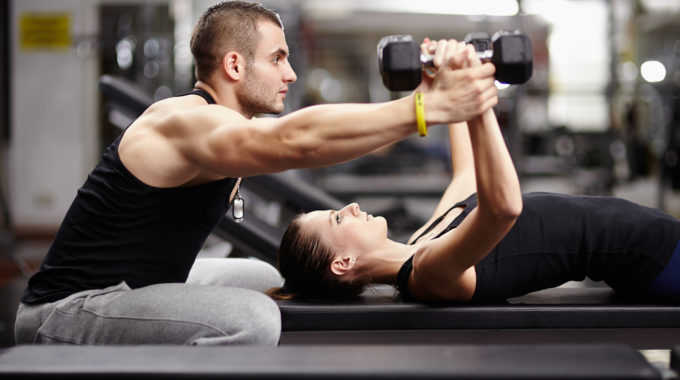 Personal Trainer Helping Woman At Gym